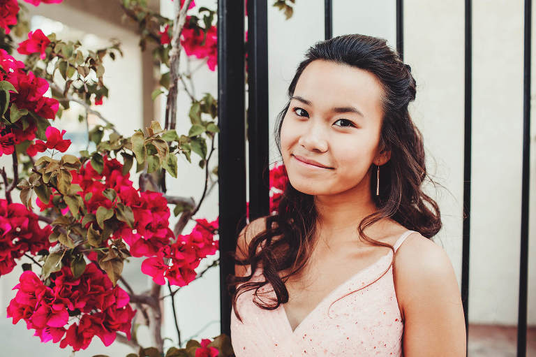 Lily standing next to brilliant pink bougainvillea during her prom session at St. Phillips Plaza