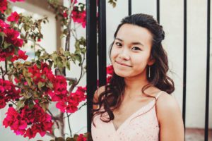 Lily standing next to brilliant pink bougainvillea during her prom session at St. Philip's Plaza