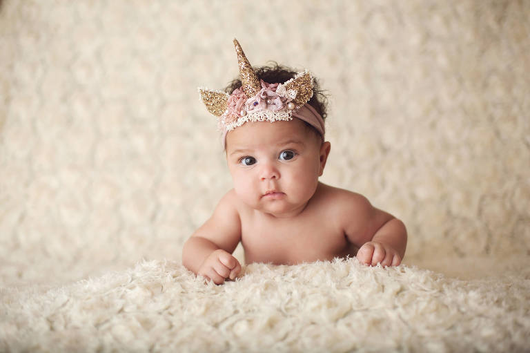 Baby Aari during her three-month milestone session in a glittery unicorn headband.