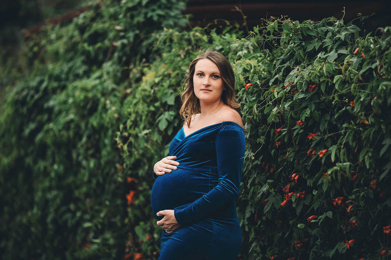 A beautiful urban maternity session near a fence covered in orange blooms