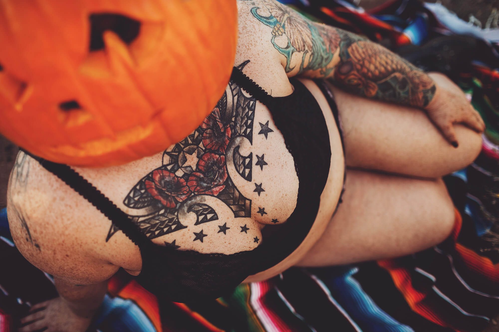 A woman poses with a jack-o-lantern on her head for a special desert boudoir photoshoot in the desert