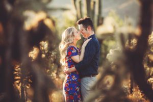 Shaun and Ally framed by jumping cactus during their engagement session at Sabino Canyon