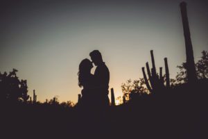 A sunset silhouette with saguaros at Sabino Canyon during their engagement session