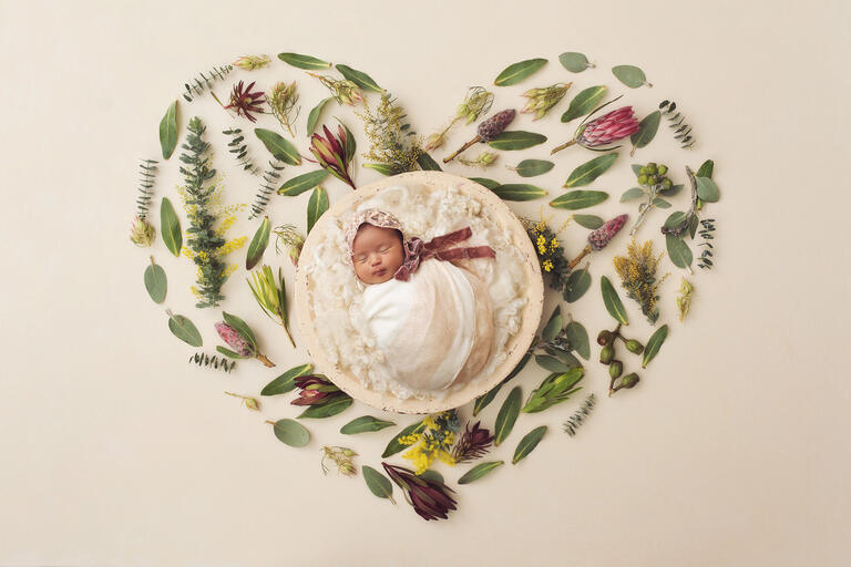 Newborn baby girl Ailani on a backdrop of a floral heart