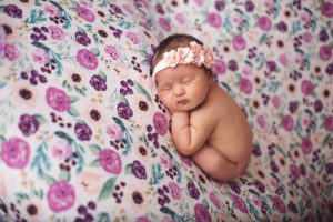Baby Ailani laying on a lavender and peach floral backdrop with a matching peach floral headband