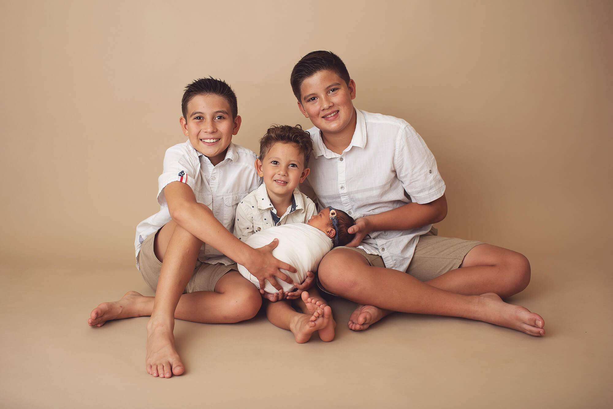 Baby girl being held by her three older brothers