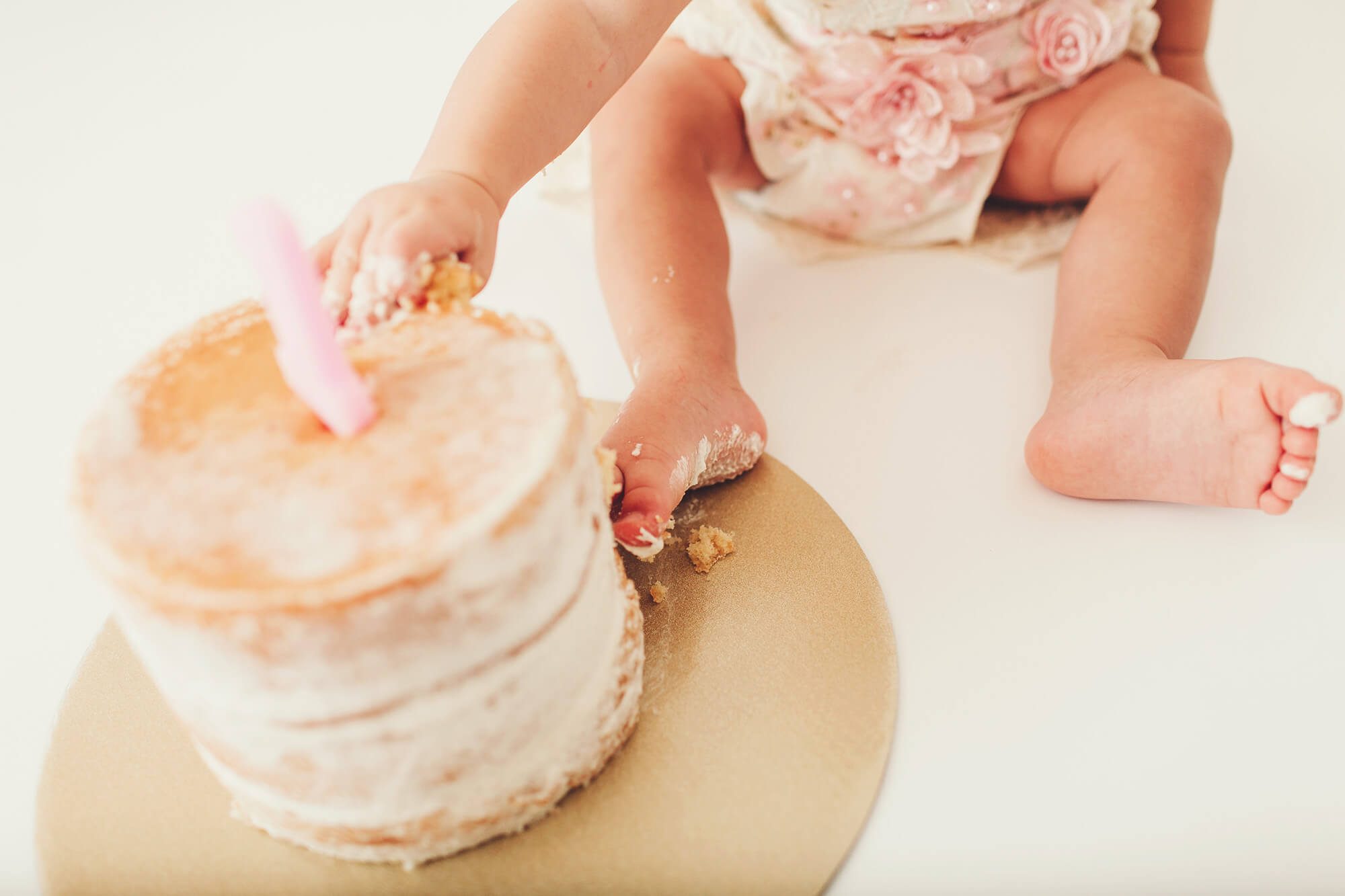 Fingers and toes covered in frosting during her birthday cake smash session