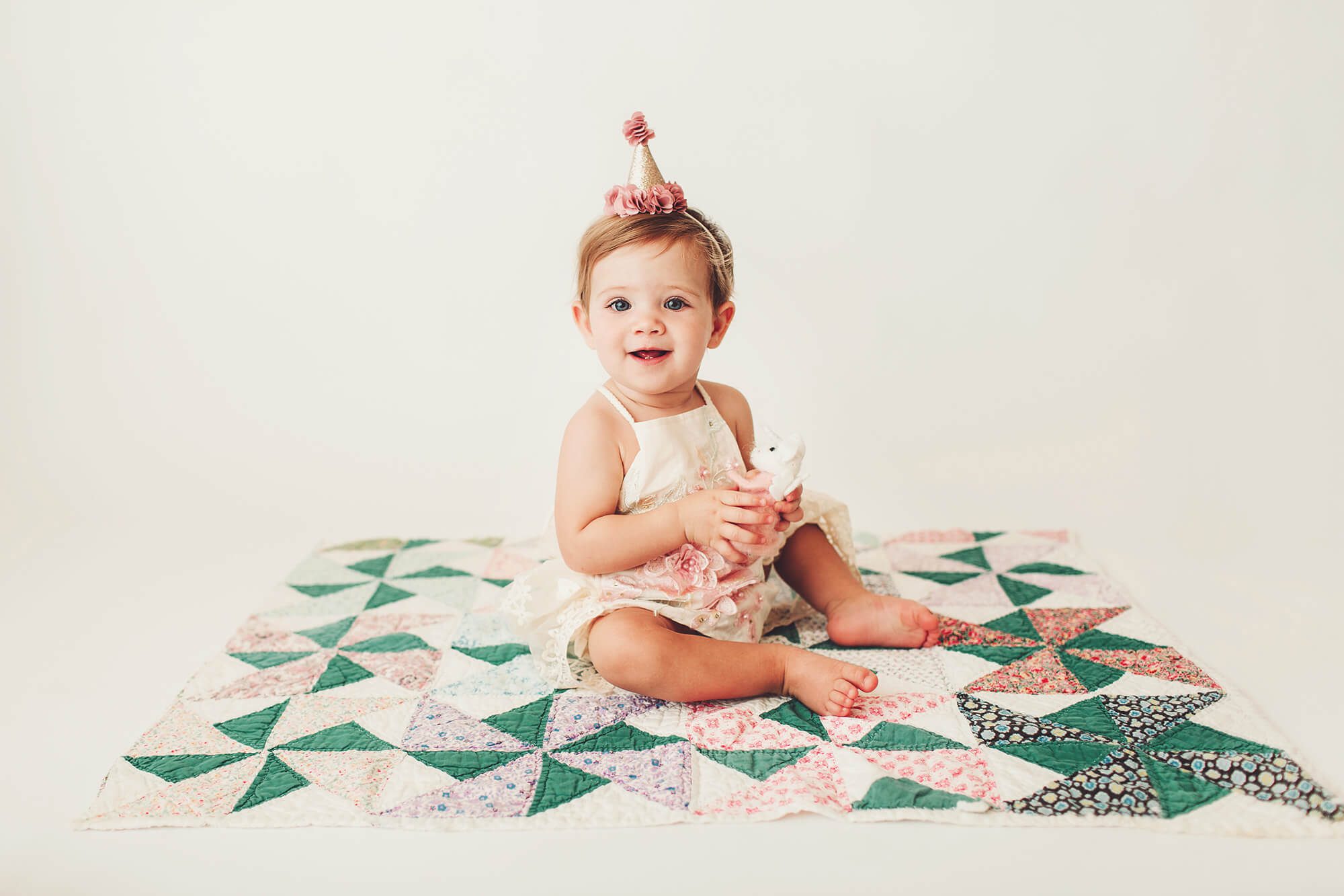 Birthday girl on an antique pastel quilt during her birthday studio session