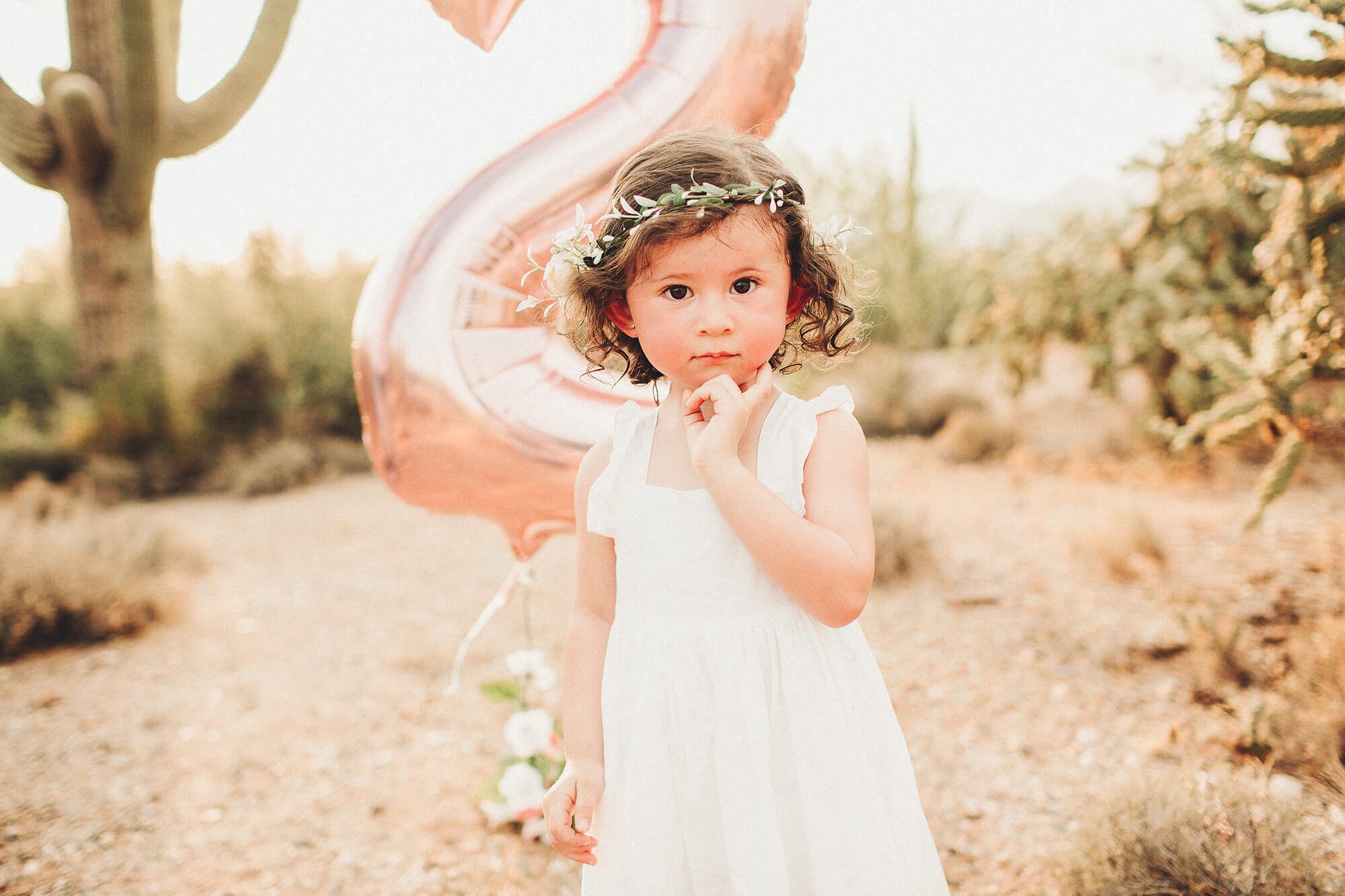 A little girl celebrates her second birthday with a floral crown and big pink balloon