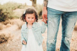 A little girl holding her daddy's hand during their desert family session at Saguaro National Park