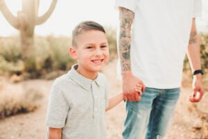 A son holding his father's had with a gorgeous saguaro at the back and the setting sun of Arizona