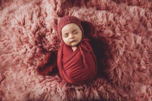 Amelia in dark pink with a sweet bonnet on flokati