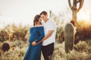 Mom and dad holding Adrianne's maternity bump during their desert photo session
