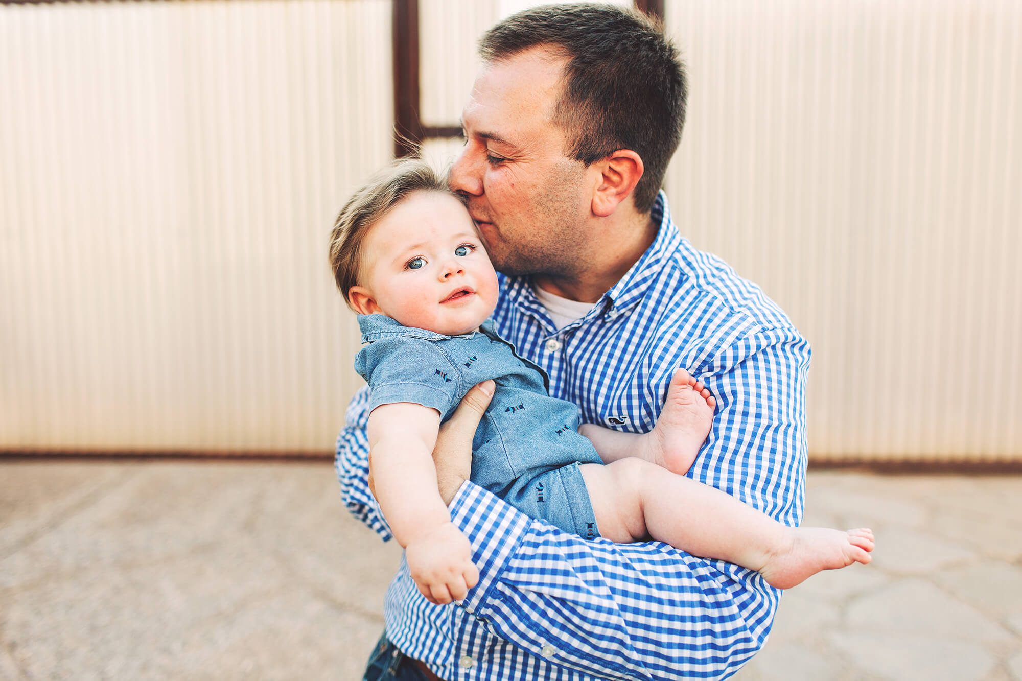 A father kisses his baby boy during their family photo session downtown.