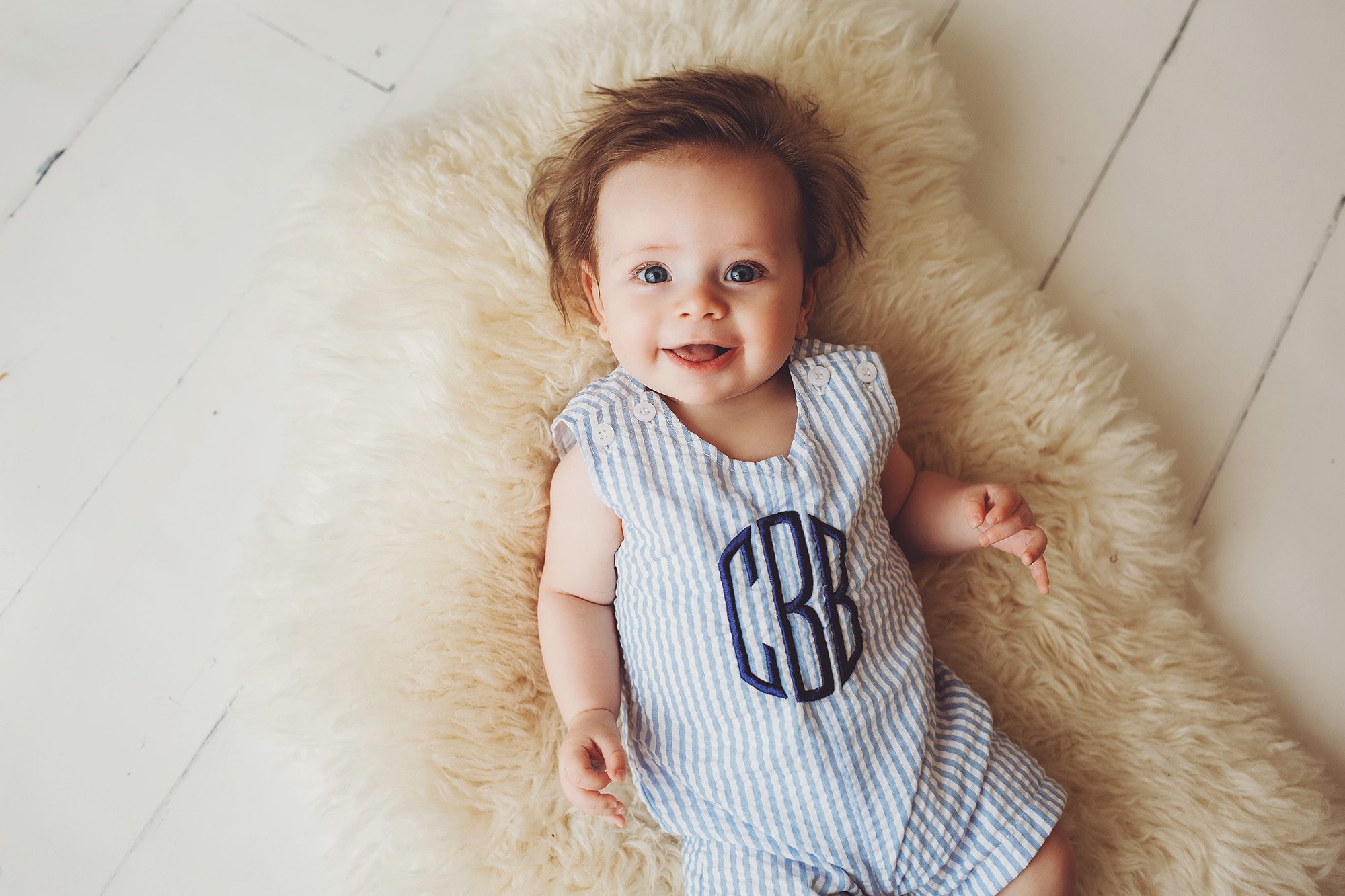Carter with a great big grin in his monogrammed onesie