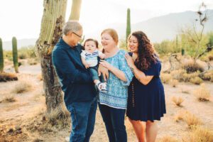Grandma, Grandpa, and Auntie giving loves to Easton during their sunrise family session