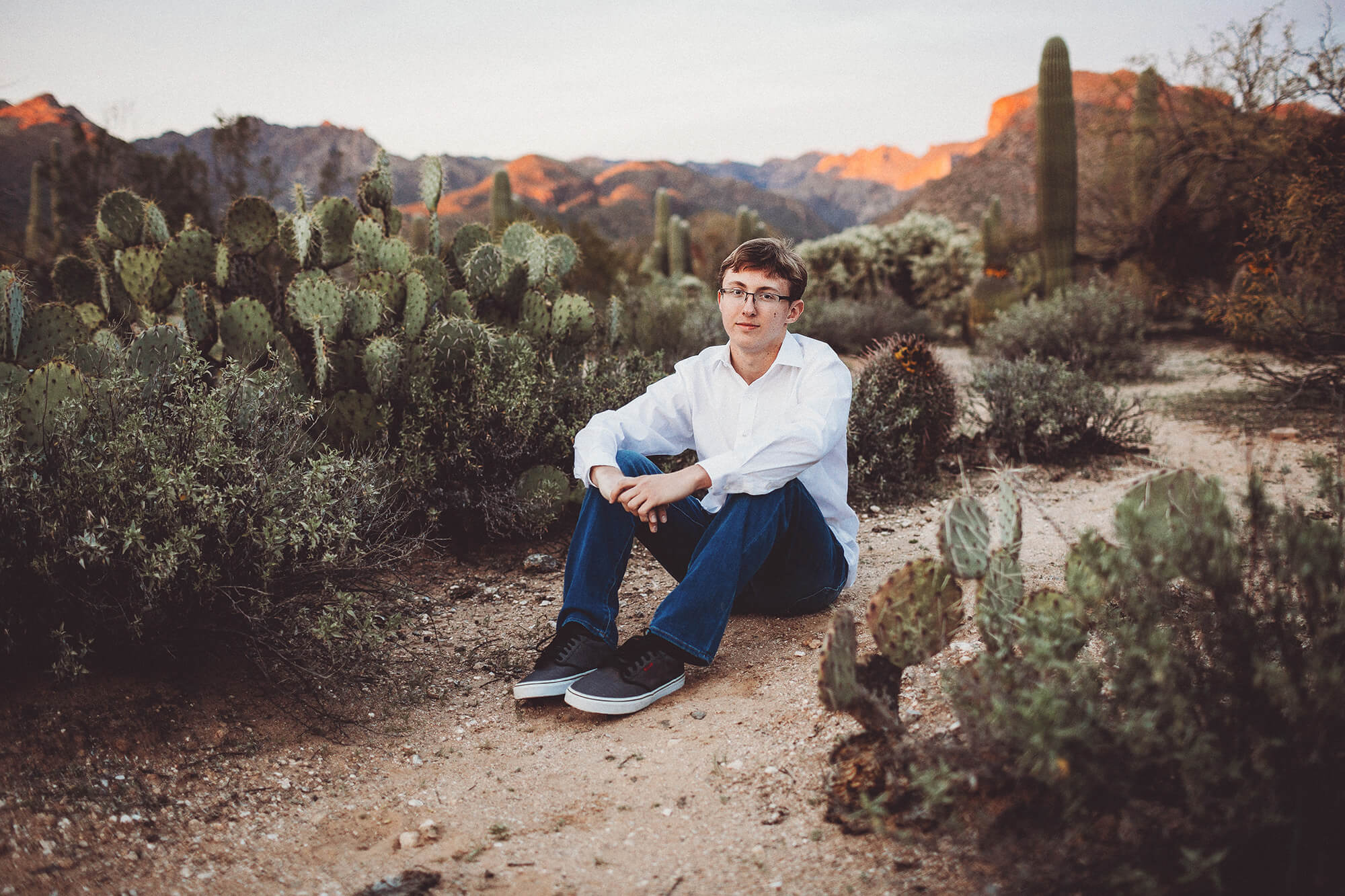 Cory sitting on the ground with the Catalina mountains behind him