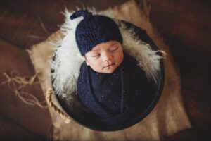 Newborn baby Oliver in a blue wrap and hat