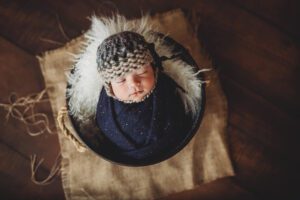 Newborn baby boy with a cute knit cap and wrapped in blue