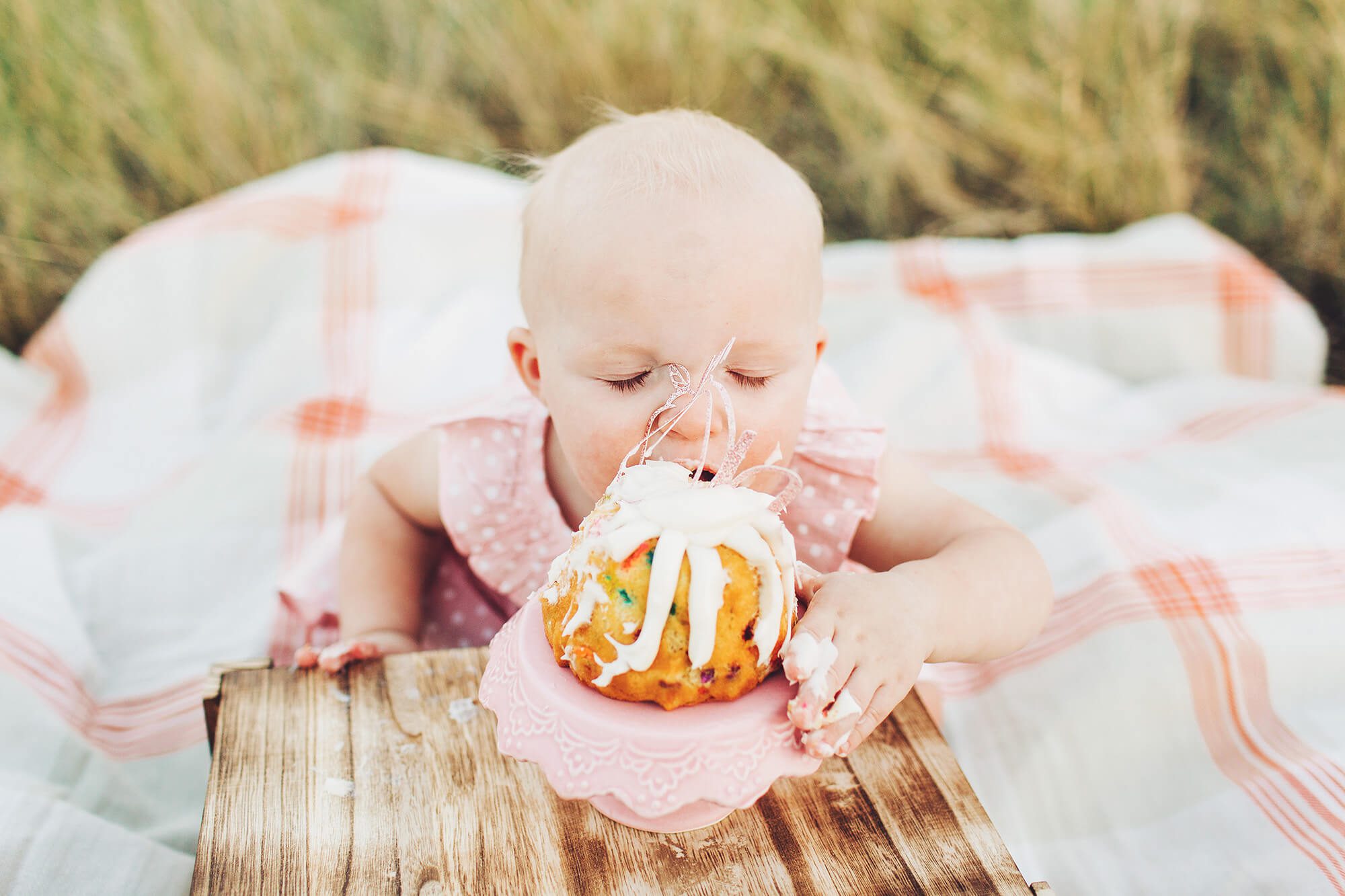 A big bite of cake for this little girl's first birthday cake smash during the Tawney Family's session.