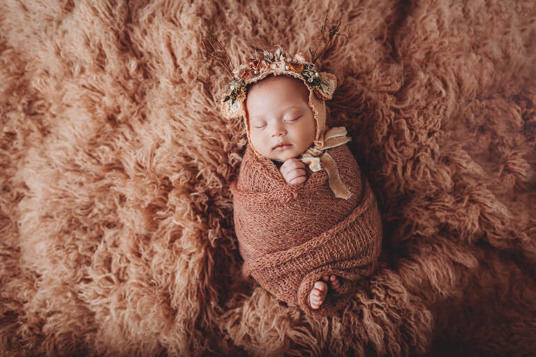Rubi's newborn session wearing a tiny deer bonnet
