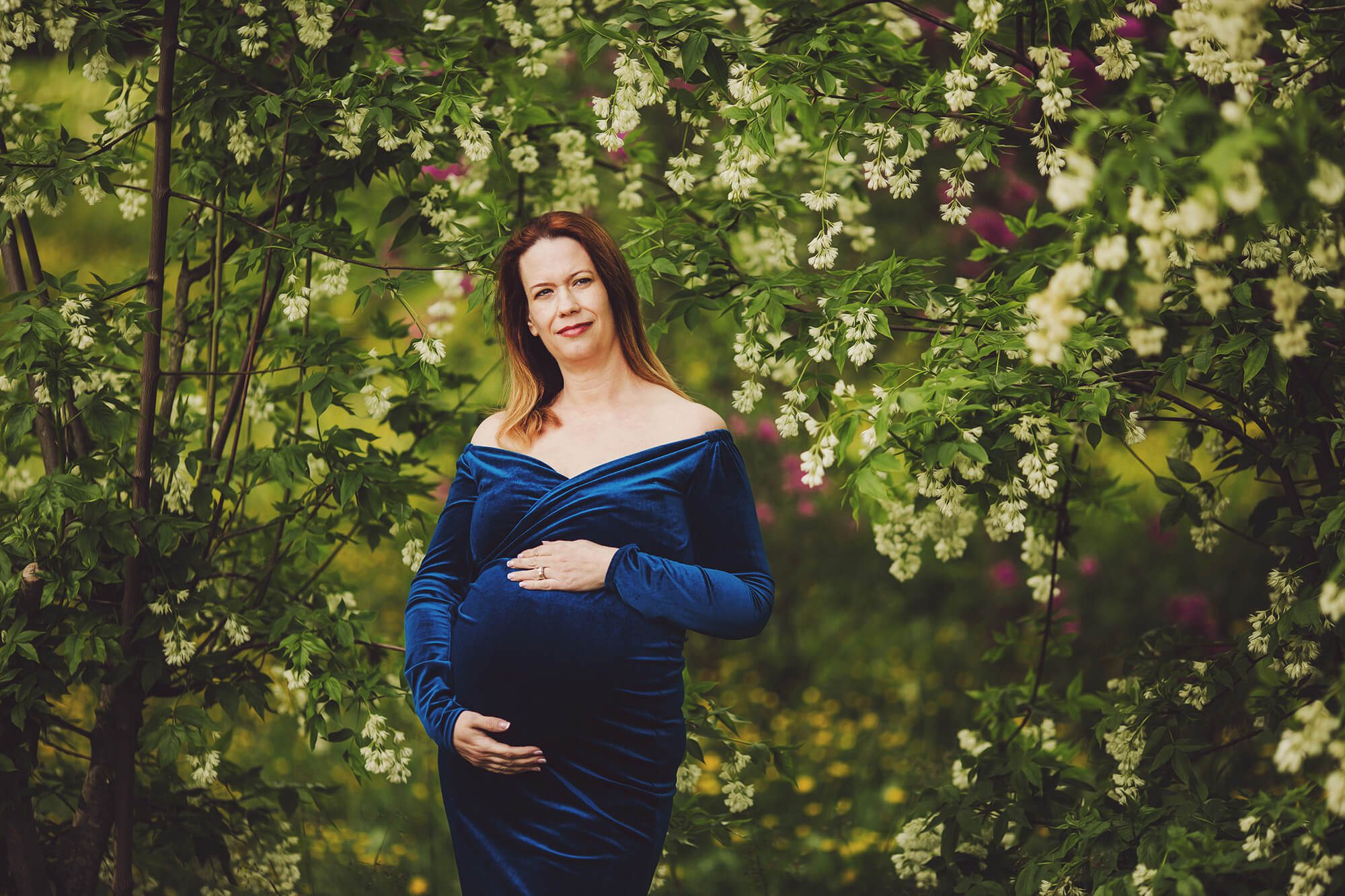 Evie during her maternity session under spring trees with white blooms